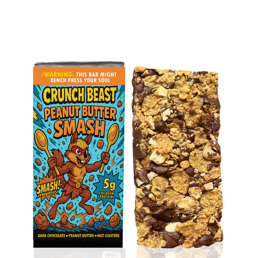 "Crunch Beast Peanut Butter Smash bar next to its packaging. The packaging features a muscular cartoon squirrel holding two golden spoons with an energetic, comic-style background in blue and orange. Text highlights '5g Collagen Protein' and 'Smash! Prebiotics', with flavor notes of dark chocolate, peanut butter, and nut clusters. The unwrapped bar shows a textured mix of chocolate, peanut butter, oats, and nut pieces."